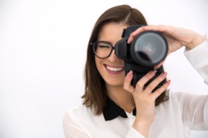 Happy female photographer with camera over gray background